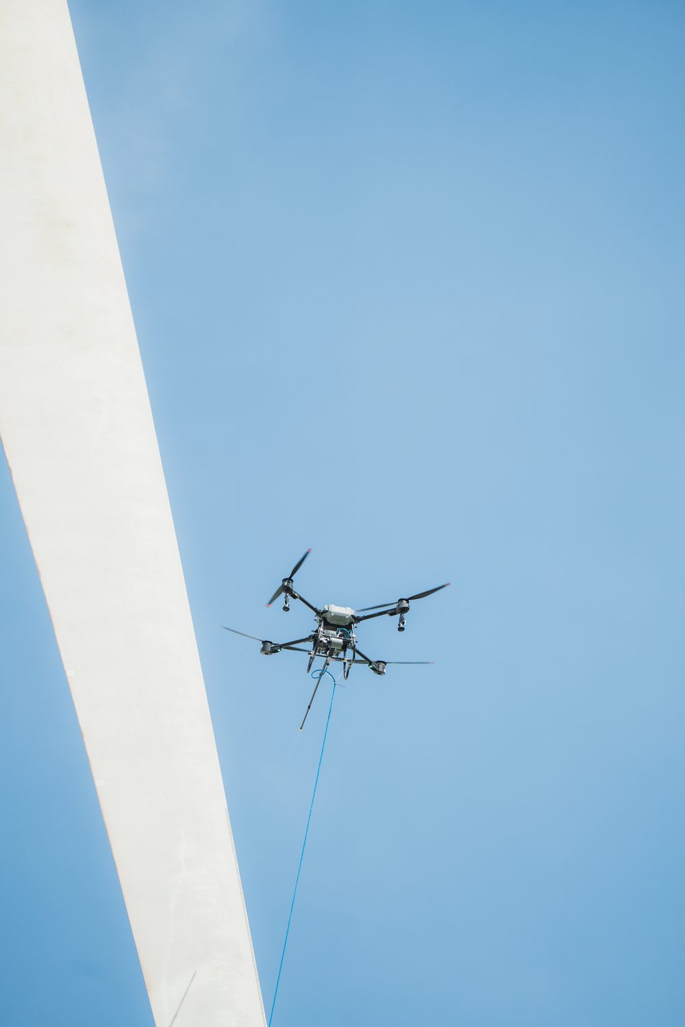 Dron de limpieza en vuelo bajo la pala de un aerogenerador