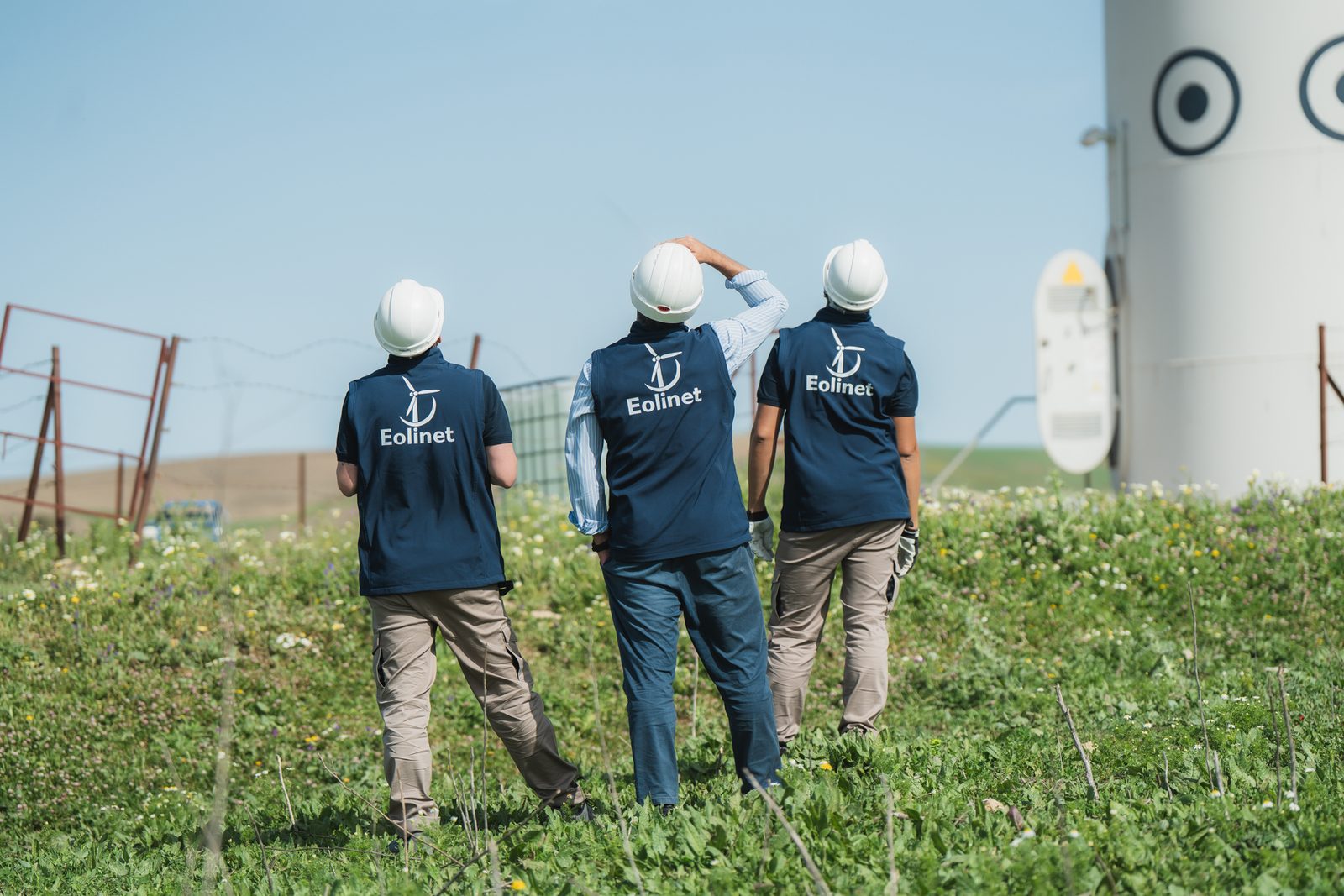 Equipo de Eolinet caminando hacia un aerogenerador en un parque eólico
