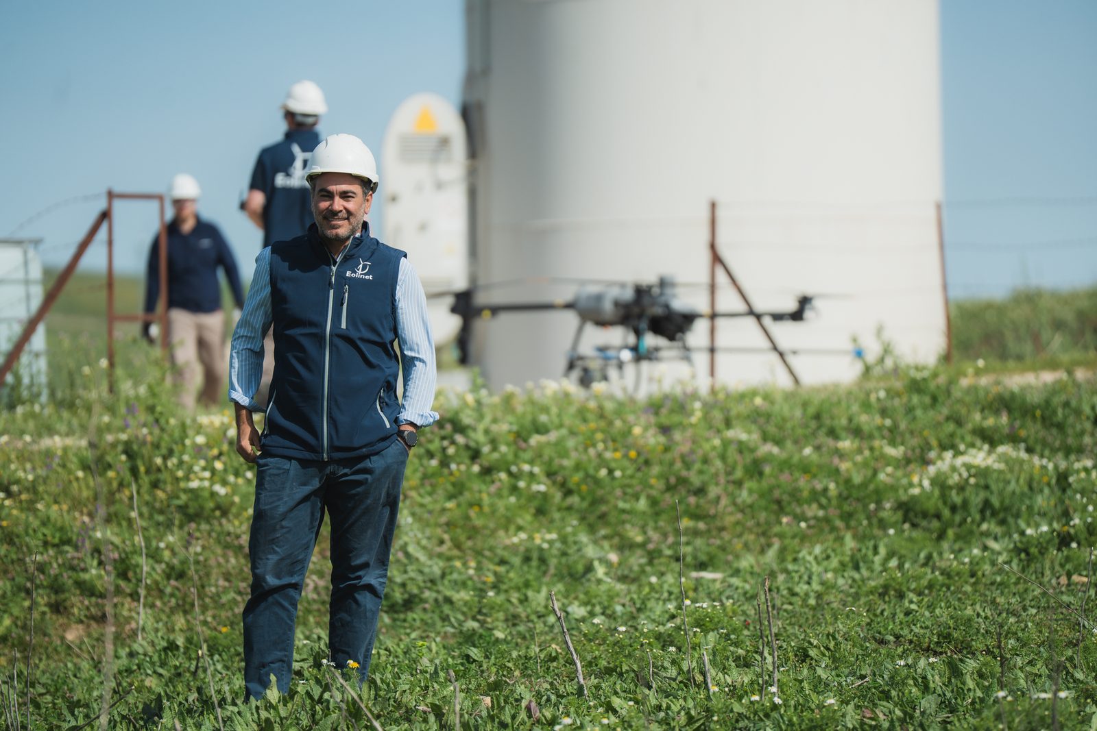 Técnico de Eolinet en un parque eólico con el dron de limpieza al fondo